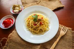 aglio e olio. italiano massa espaguete, aglio olio e calabresa ,espaguete com alhos, Oliva óleo e Pimenta pimentas em prato em mesa foto