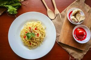 aglio e olio. italiano massa espaguete, aglio olio e calabresa ,espaguete com alhos, Oliva óleo e Pimenta pimentas em prato em mesa foto