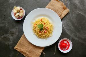 aglio e olio. italiano massa espaguete, aglio olio e calabresa ,espaguete com alhos, Oliva óleo e Pimenta pimentas em prato em mesa foto