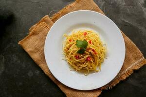 aglio e olio. italiano massa espaguete, aglio olio e calabresa ,espaguete com alhos, Oliva óleo e Pimenta pimentas em prato em mesa foto