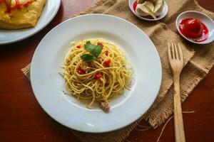 aglio e olio. italiano massa espaguete, aglio olio e calabresa ,espaguete com alhos, Oliva óleo e Pimenta pimentas em prato em mesa foto