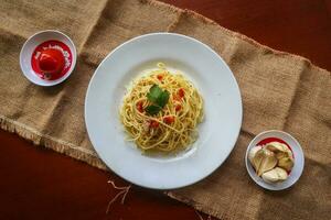 aglio e olio. italiano massa espaguete, aglio olio e calabresa ,espaguete com alhos, Oliva óleo e Pimenta pimentas em prato em mesa foto