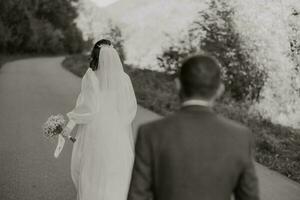 a noivo segue a noiva, anda em baixa a estrada, a noiva é dentro uma luz, lindo vestir. a conceito do uma Casamento e uma Casamento foto sessão debaixo a aberto céu