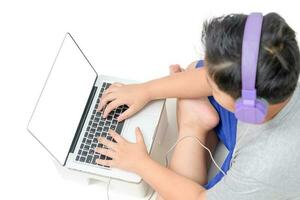 Garoto aluna jogando computador em em branco tela com fones de ouvido foto