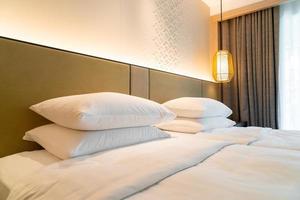decoração de travesseiro branco na cama em um quarto de hotel resort foto
