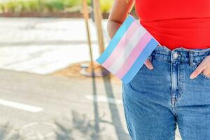 gênero queer. mulher aguarde transgêneros bandeira durante orgulho mês celebração. seletivo foco. foto