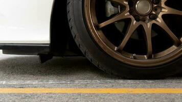 baixa Visão do ouro Liga rodas do Esportes carros. carro branco cor Pare dentro a estacionamento muitos com amarelo linha em asfalto estrada. foto