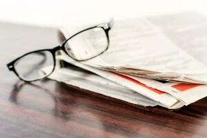 jornal e lendo óculos em de madeira mesa. foto