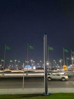 jedá, saudita Arábia, Junho 2023 - uma lindo Visão do saudita árabe bandeiras vôo às Jeddah corniche estrada interseção às noite. foto