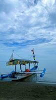 uma barco em a de praia água com azul céu e nuvens dentro a fundo foto