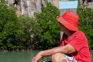 homem asiático sênior viajar em um barco de cauda longa para ver a floresta de mangue nas férias de verão foto