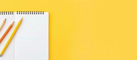 dois lápis e uma bloco de anotações em uma amarelo fundo criada com generativo ai tecnologia foto