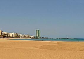 calma arenoso de praia dentro uma espanhol Cidade em a azul oceano foto
