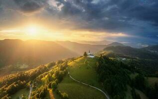 aéreo Visão do pequeno Igreja em a montanha pico às pôr do sol foto