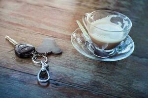 café copo e carro chaves em a de madeira mesa.depois bebendo café foto
