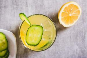 fechar acima do refrescante limonada com limão, pepino e gelo dentro uma vidro em a mesa topo Visão foto