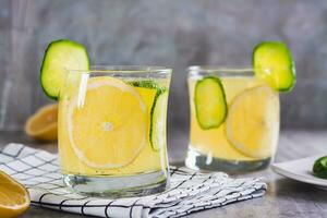 refrescante limonada com limão, pepino e gelo dentro óculos em a mesa foto