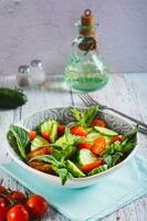 fresco salada do pepinos, cereja tomates e hortelã folhas dentro uma tigela em a mesa vertical Visão foto