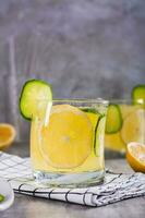 refrescante limonada com limão, pepino e gelo dentro óculos em a mesa vertical Visão foto