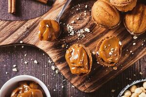 fechar acima do noz em forma biscoitos preenchidas com fervido condensado leite em uma borda topo Visão foto