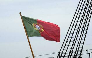 Português bandeira acenando dentro a vento em uma navio dentro Lisboa foto