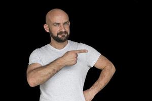 homem careca branco com barba em uma camiseta branca apontando o dedo para o lado