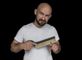 um carpinteiro careca barbudo com uma serra corta o dedo e isola com segurança em um fundo preto foto