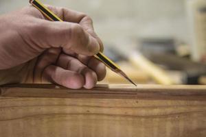 carpinteiro com um lápis marca a peça de trabalho foto