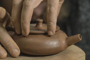 oleiro esculpe um bule chinês de argila roxa foto