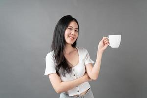 jovem mulher asiática com um rosto feliz e uma mão segurando uma xícara de café foto