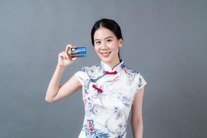 Mulher asiática usando vestido tradicional chinês com a mão segurando um cartão de crédito foto