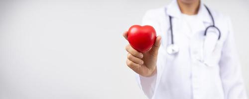 feche a mão de um médico segurando um coração vermelho por causa de doenças cardíacas, conceito de serviço de seguro saúde