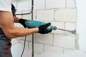 homem com martelo de demolição remove estuque da parede. conceito de renovação foto