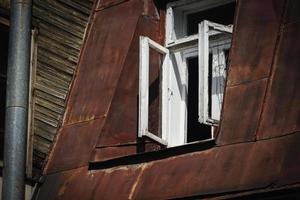 madeira escura e parede de construção marrom de metal enferrujado com janela branca aberta foto