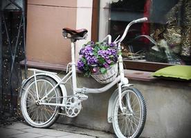 bicicleta branca com cesto de flores perto da loja foto