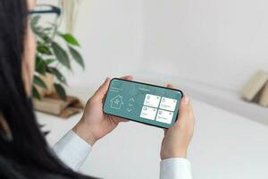 integração do tecnologia e casa conforto conceito. mulher segurando uma Móvel telefone, controlando uma inteligente casa aplicativo foto