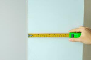 mão de homem usando fita métrica para medir móveis em casa. diy, design de interiores, reparação e melhoria de conceitos de casa ou apartamento foto