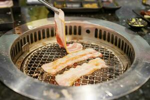 mão grelhar carne carne de porco em fogão servir dentro restaurante. japonês Comida e coreano churrasco tradicional estilo foto