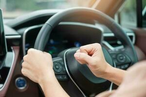 motorista de mulher buzinando um carro durante a condução na estrada de tráfego, mão controlando o volante no veículo. conceitos de transporte de viagem, viagem e segurança foto