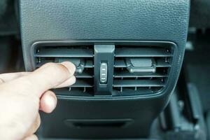 mão de mulher ajustando a temperatura do ar que flui durante a condução do carro na estrada, sistema de refrigeração do ar condicionado dentro do carro. ajuste, temperatura e conceito de transporte foto