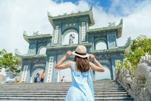 mulher viajante visitando às linh ung pagode têmpora, tradução a partir de chinês personagem. turista com azul vestir e chapéu viajando dentro da nang cidade. Vietnã e sudeste Ásia viagem conceito foto