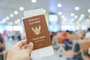 mão segurando Tailândia Passaporte e embarque passar bilhete dentro internacional aeroporto. viagem, período de férias e transporte conceitos foto