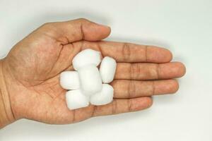 mão segurando algodão bolas em branco fundo. foto