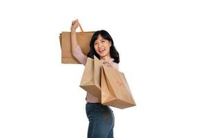 jovem feliz ásia mulher com casual camisa e jeans jeans segurando compras papel saco isolado em branco fundo foto