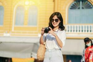 retrato do ásia mulher viajante usando Câmera. Ásia verão turismo período de férias conceito foto