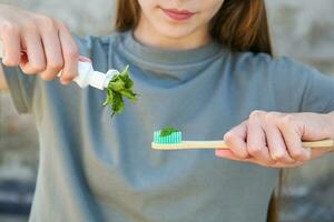 a menina detém uma escova de dente com hortelã dentro dela mão. seletivo foco em a hortelã escova de dente. foto