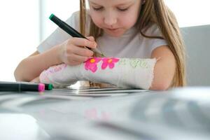 uma pequeno menina tintas uma fundida em dela braço. uma criança desenha uma desenhando em uma fundida depois de uma mão ferida. foto