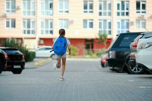 uma estudante menina corre com uma pasta em dela costas para escola. costas para escola. foto
