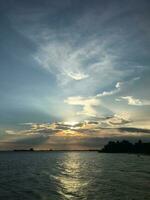 foto do a pôr do sol céu com uma mar Visão e ilha silhueta