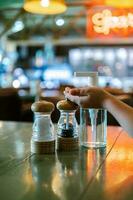 uma sal e Pimenta agitador e a antisséptico ficar de pé em a mesa dentro uma Barra ou cafeteria. foto